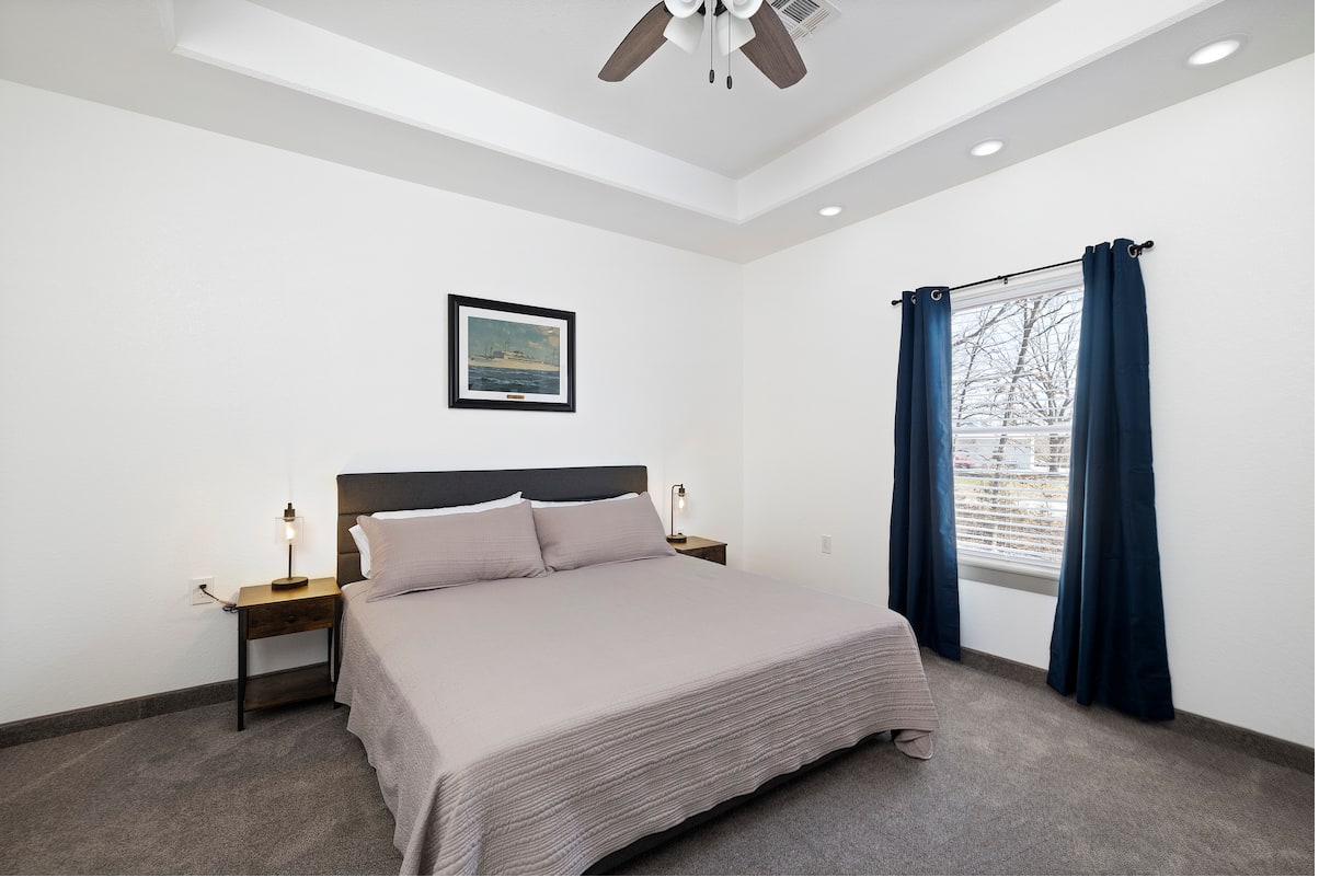 Master bedroom — wide view with ship painting & navy curtains