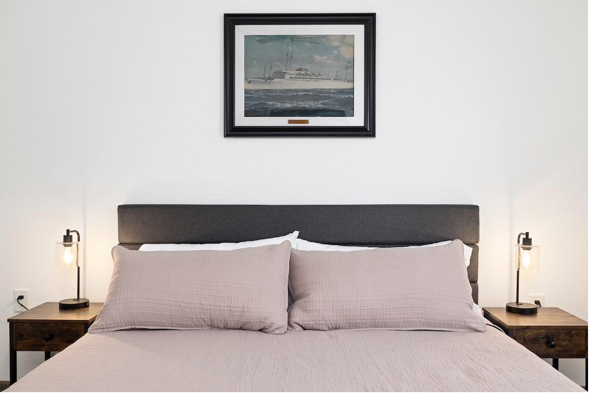Master bedroom — headboard with ship painting & bedside lamps